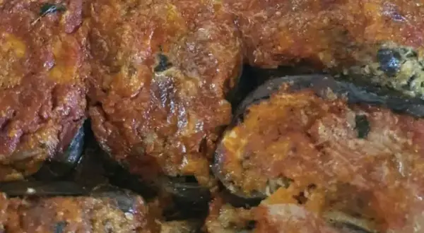 Melanzane ripiene calabresi, un piatto ricco e saporito, con un ripieno gustoso e una salsa rossa invitante.