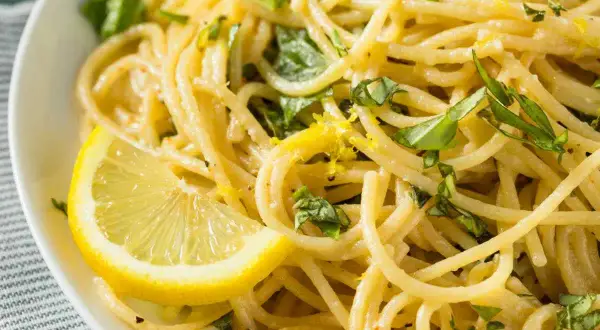 Spaghetti al limone, un sapore di Costiera Amalfitana. Pasta fresca con scorza di limone e basilico, guarnita con una fetta di limone.