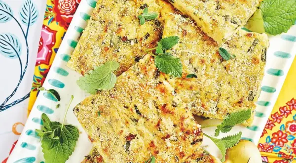 Fette dorate di polpette vegetariane, croccanti fuori e morbide dentro, guarnite con erbe fresche su un piatto decorato.
