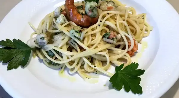 Un piatto invitante di pasta con mazzancolle, condita con erbe fresche e un filo d'olio.