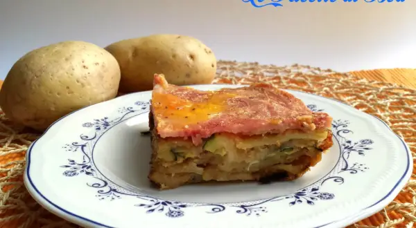 Una fetta di parmigiana di zucchine e patate, con prosciutto e formaggio fuso, servita su un piatto decorato.