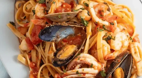 Un piatto invitante di scialatielli allo scoglio, con gamberi, cozze, vongole e calamari in un sugo rosso.