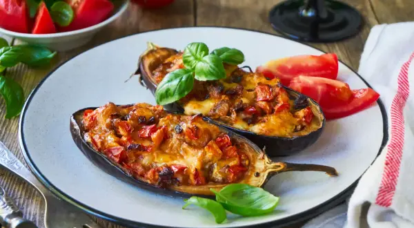 Melanzane ripiene senza carne, dorate e filanti, guarnite con basilico fresco. Un piatto vegetariano invitante.