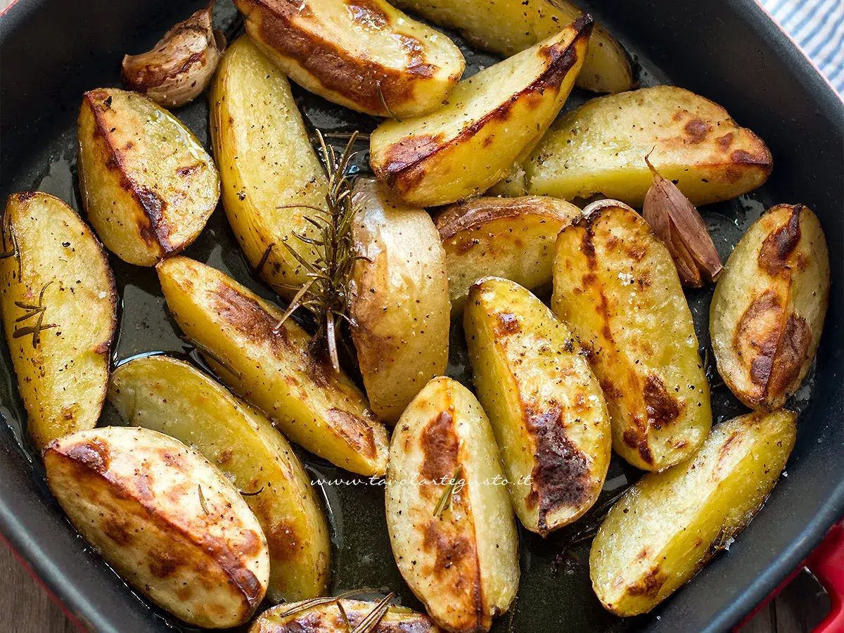 Patate con la buccia dorate al forno, condite con rosmarino e aglio. Un contorno rustico e saporito.