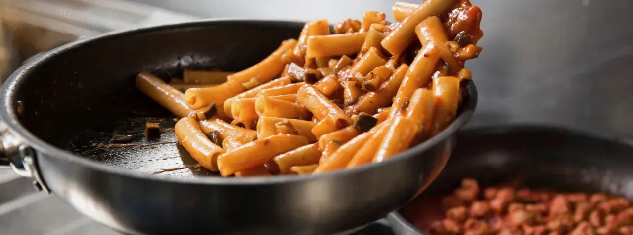 Rigatoni conditi con un sugo ricco e saporito, pronti per essere serviti. Un classico piatto di pasta al pomodoro che fa venire l'acquolina in bocca.