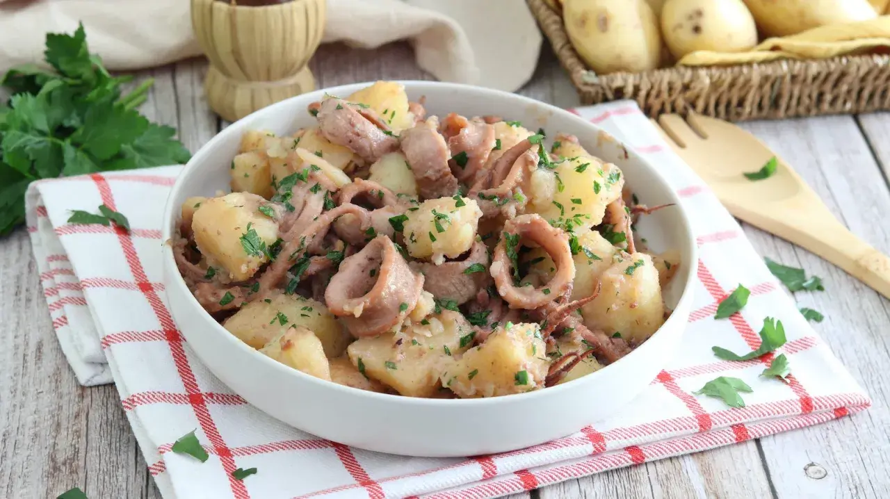 Un gustoso piatto di totani e patate, condito con prezzemolo fresco, pronto per essere gustato.
