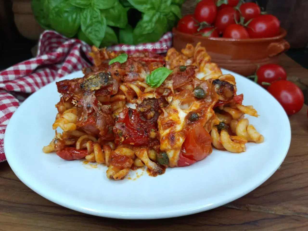 Piatto di pasta con pomodori al forno alla pugliese, filante e saporita, guarnita con basilico fresco.
