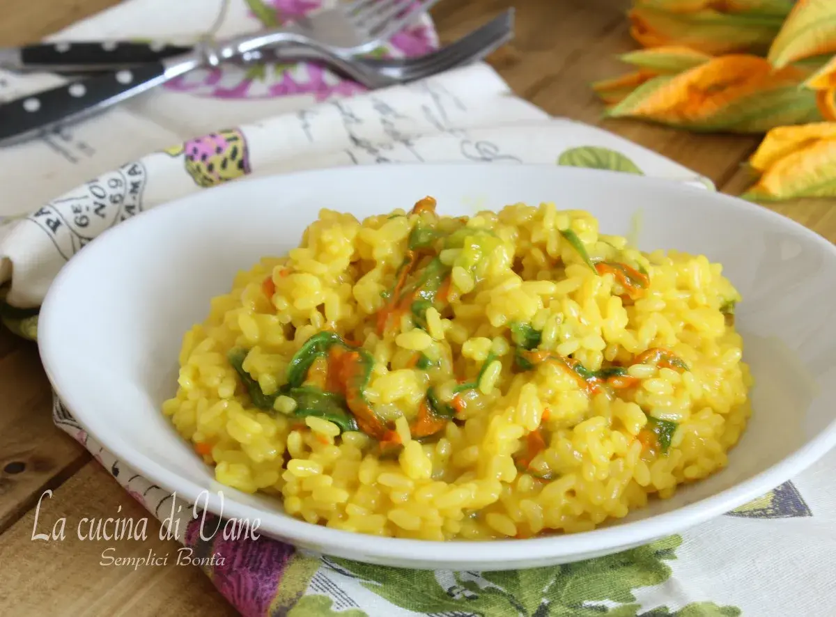 Un invitante risotto ai fiori di zucca cremoso, con petali arancioni e verdi che si mescolano al riso giallo dorato.