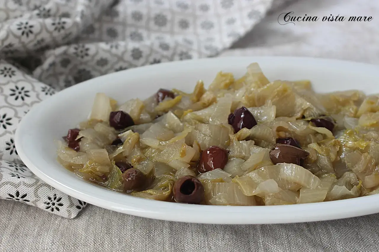 Indivia belga saltata in padella con olive nere, un piatto semplice e gustoso.