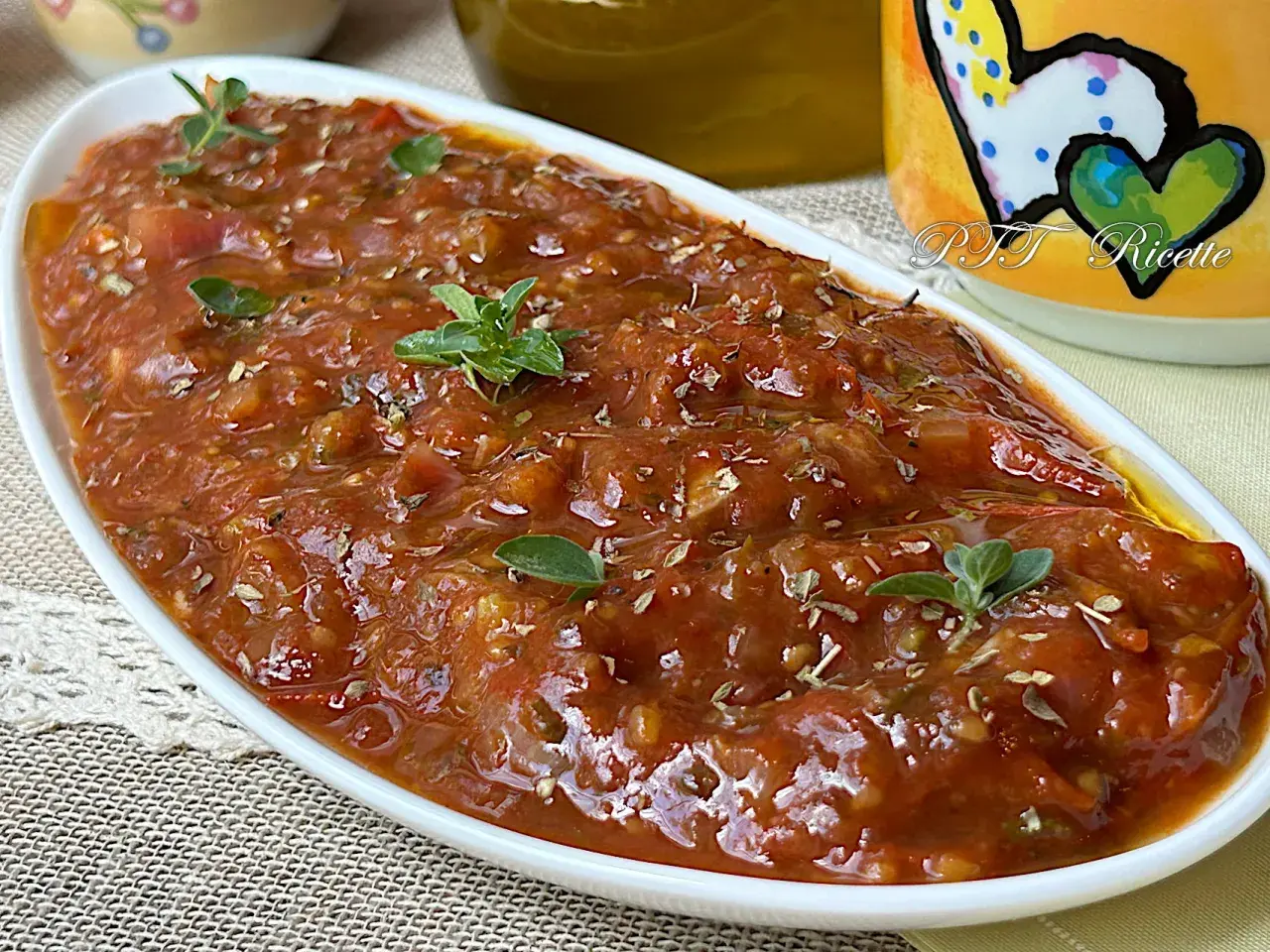 Sugo con pomodorini freschi, profumato con erbe aromatiche, servito in una ciotola bianca.