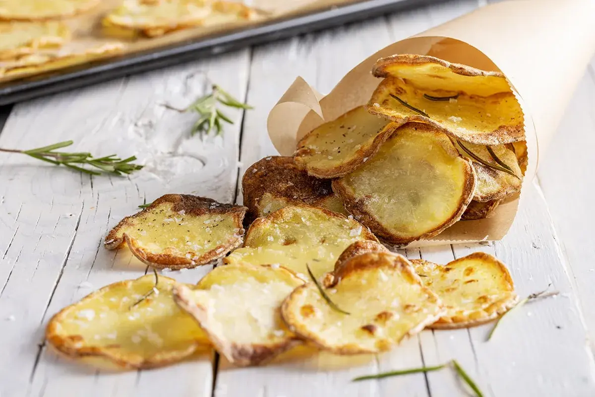 Patate al forno veloci, croccanti e dorate, condite con sale e rosmarino, servite in un cono di carta.