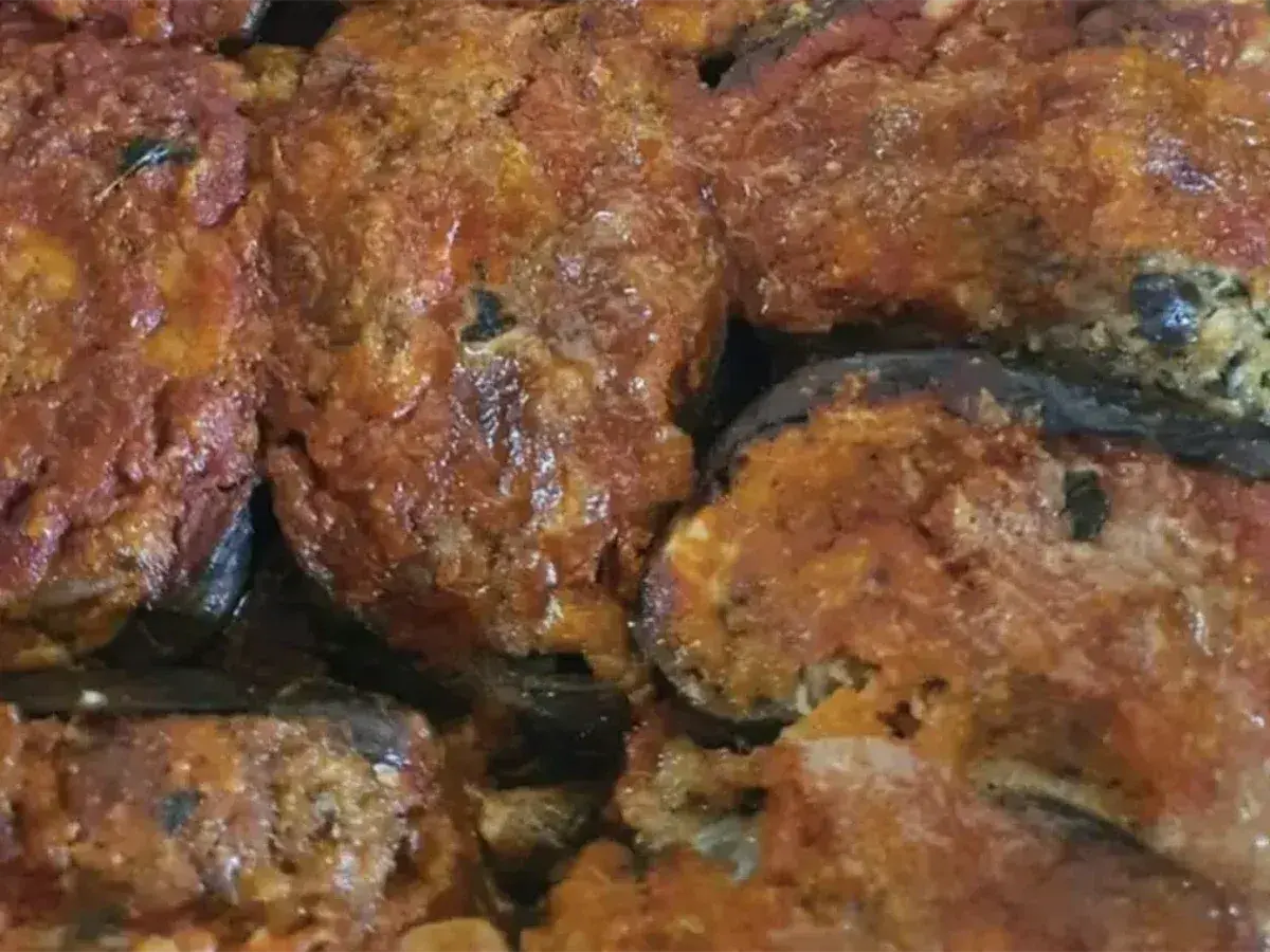 Melanzane ripiene calabresi, un piatto ricco e saporito, con un ripieno gustoso e una salsa rossa invitante.