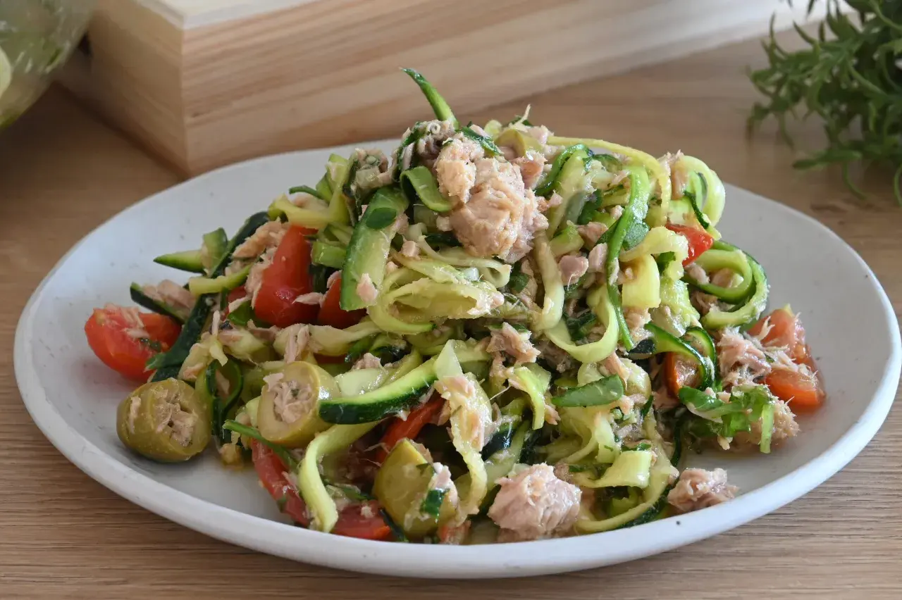 Deliziosa insalata di zucchine a spirale con tonno, pomodorini e olive verdi, un piatto fresco e leggero.