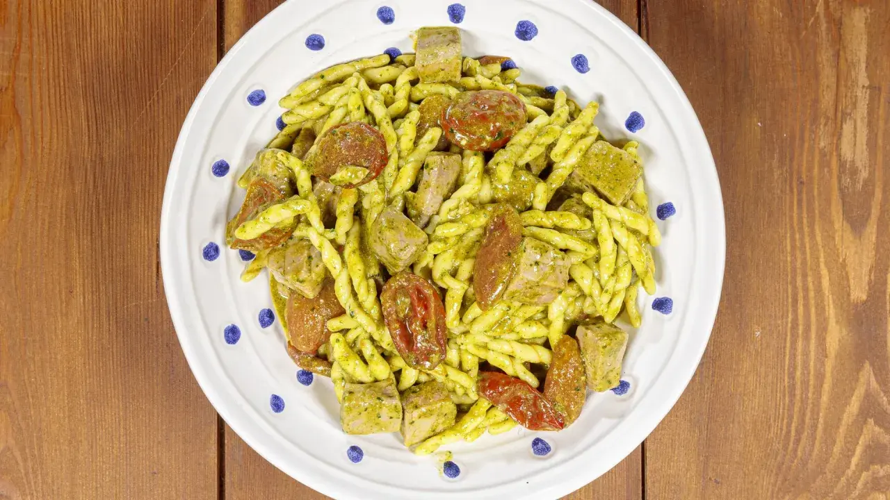 Un piatto di pasta alla carlofortina con trofie condite con pesto, pomodorini secchi e cubetti di tonno.
