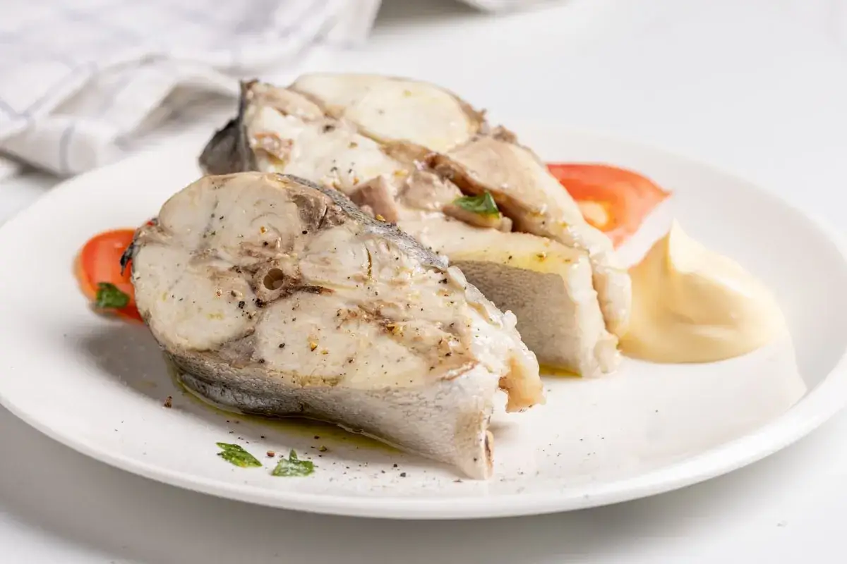 Fette di ricciola cotta al vapore, servite con pomodoro e maionese. Un'idea per le tue ricette di pesce.