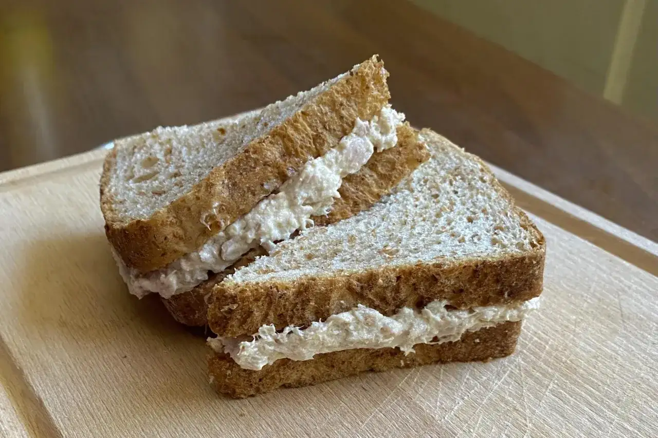 Due fette di pane integrale con abbondante salsa tonnata e uova sode, pronte per un pasto veloce.