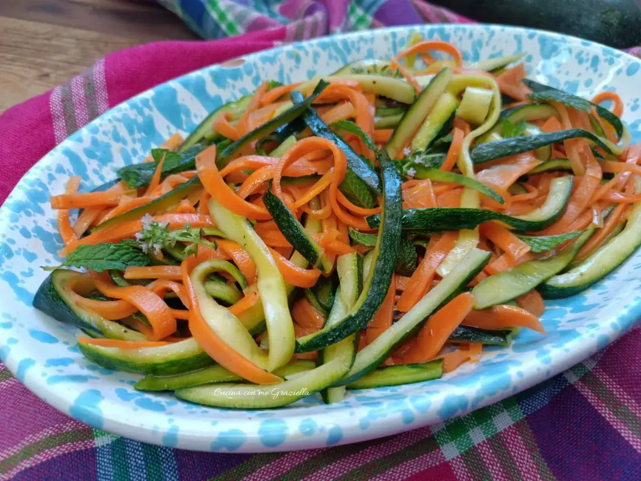 Deliziosa insalata di zucchine e carote a julienne, guarnita con menta fresca. Un piatto leggero e colorato.