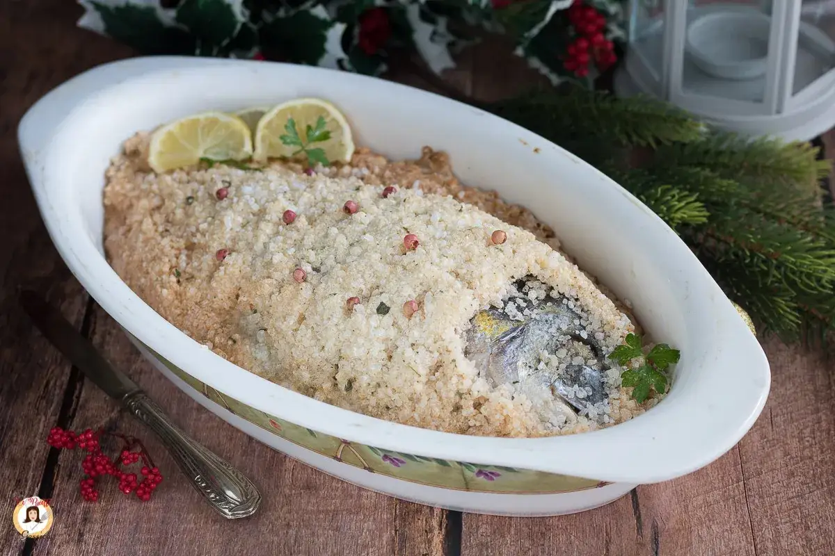 Orata al sale, cotta in crosta di sale grosso, guarnita con limone e pepe rosa. Un piatto elegante per le feste.