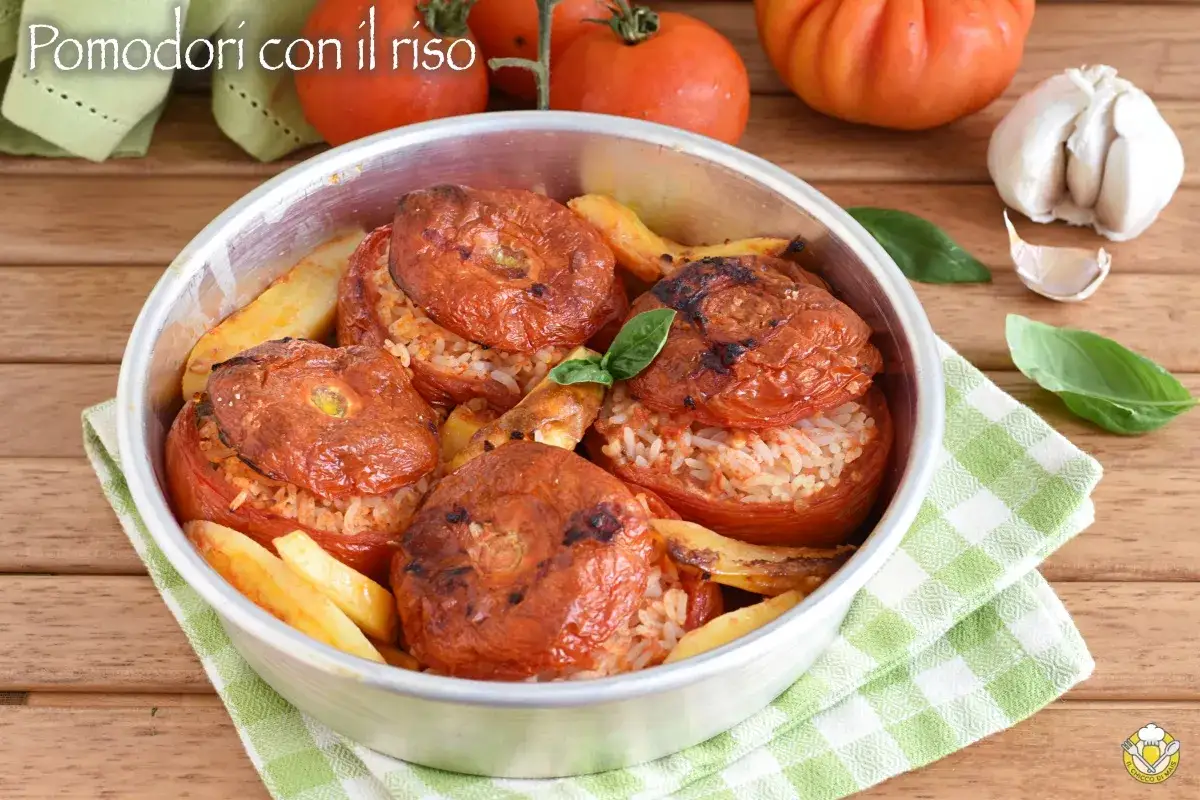 Pomodori ripieni di riso, cotti al forno con patate e basilico, un piatto estivo saporito.