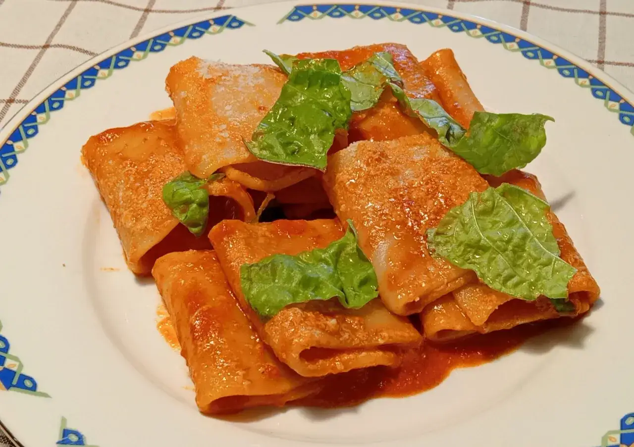Paccheri alla Vittorio, un piatto gustoso con sugo rosso e basilico fresco.