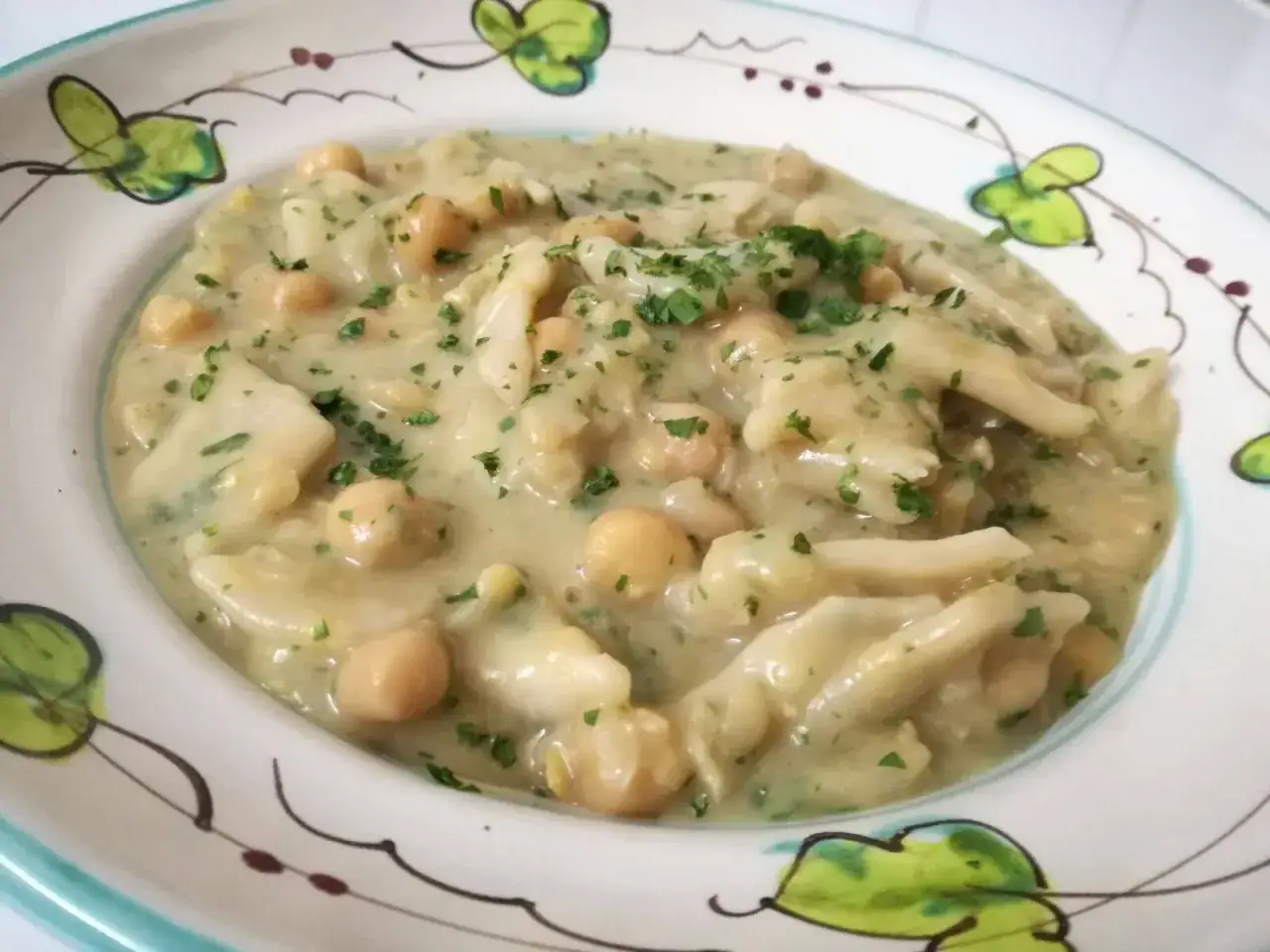 Lagane e ceci cremose, un piatto tradizionale ricco di sapore, guarnito con prezzemolo fresco.