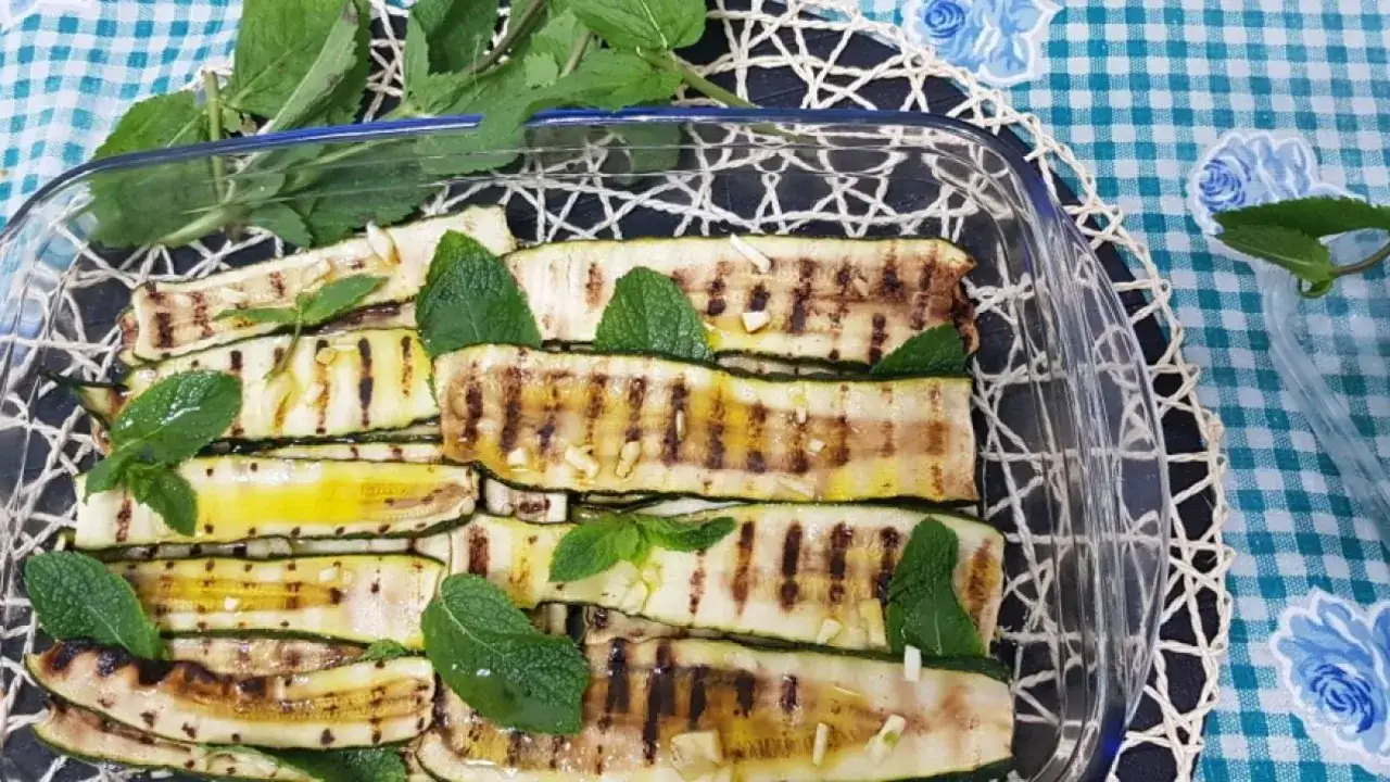 Zucchine grigliate condite con aglio, olio e menta fresca. Un contorno leggero e saporito, perfetto per ogni occasione.