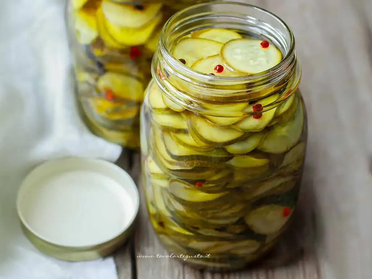 Vasi di zucchine sott'olio, affettate finemente e conservate in olio, con qualche grano di pepe rosso.