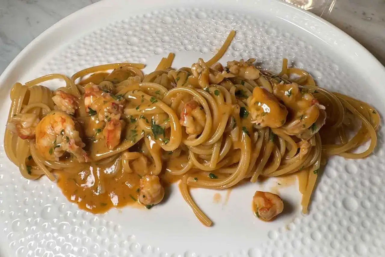Spaghetti cremosi con mazzancolle e prezzemolo tritato, un piatto invitante che profuma di mare.