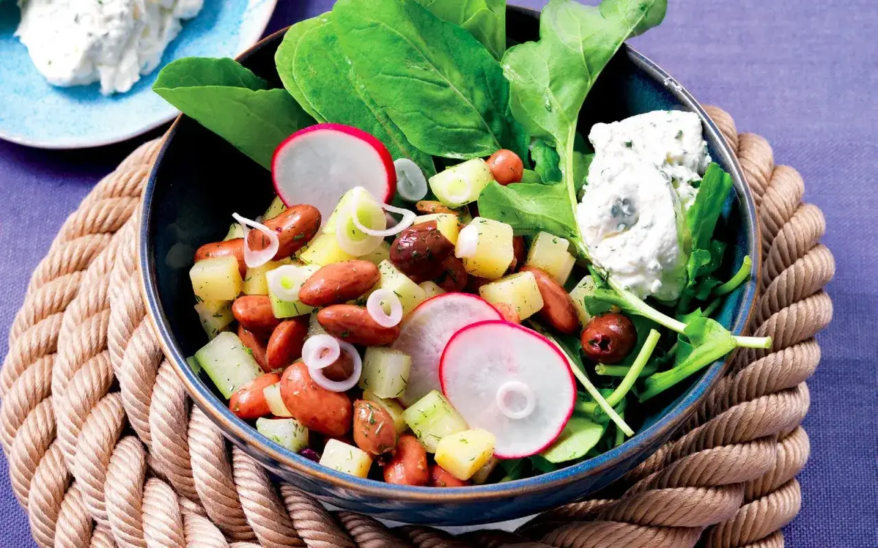 Insalata ricca con patate, fagioli, salsicce e ravanelli, condita con una fresca salsa allo yogurt per insalata.