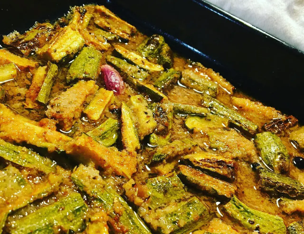 Zucchine in carpione, un piatto saporito e colorato, con pezzi di zucchina dorati e immersi in una marinatura aromatica.