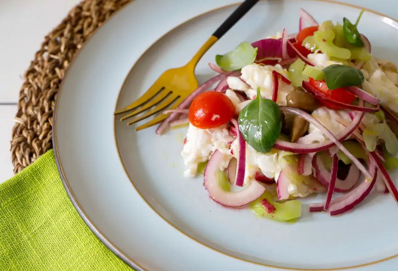 Rana pescatrice alla catalana: un piatto fresco con pesce bianco, pomodorini, cipolla rossa, sedano e olive.