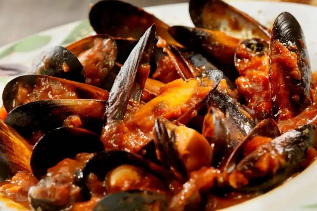 Muscoli alla marinara succulenti, immersi in una salsa rossa ricca e saporita, pronti per essere gustati.