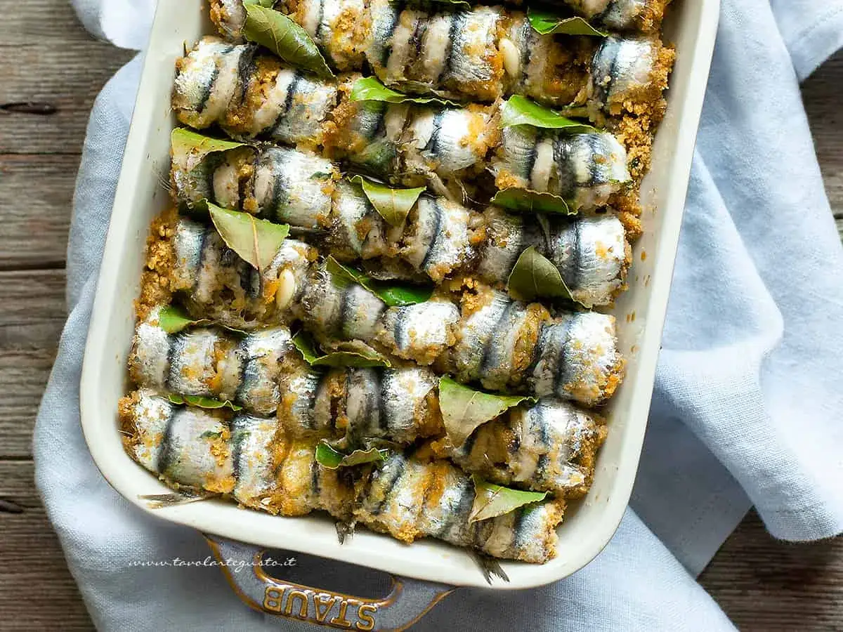 Sardine ricette: involtini di sarde impanate e cotte al forno, guarnite con foglie di alloro.