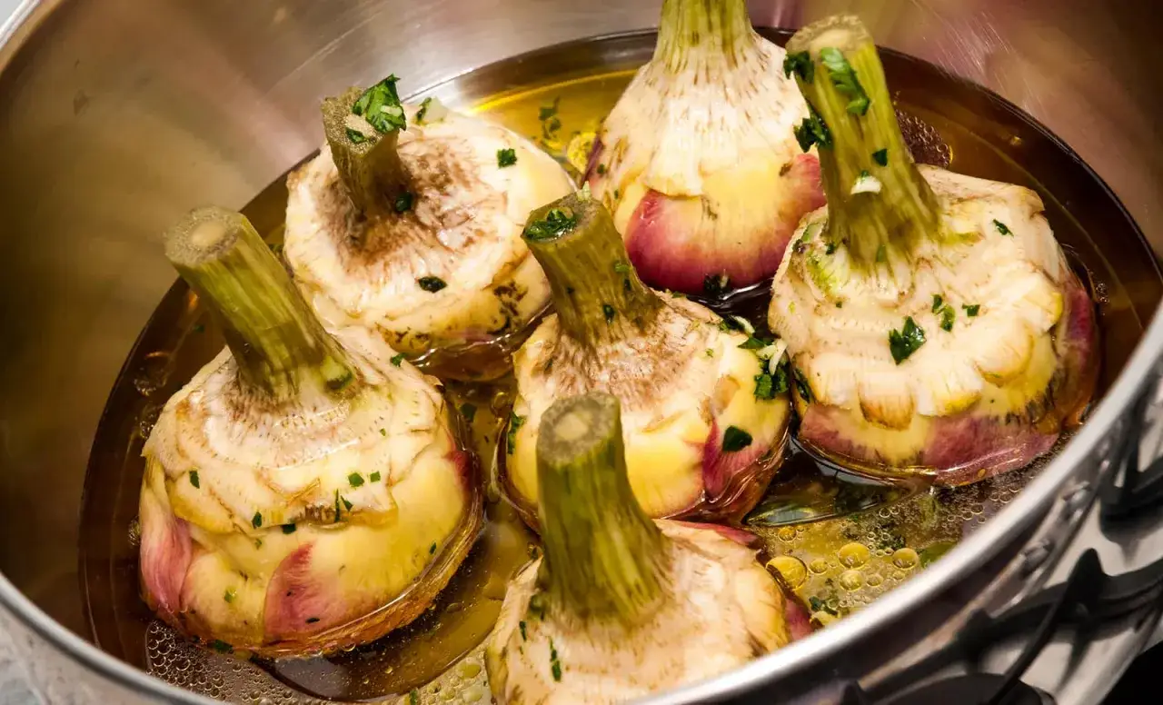 Carciofi alla giudia in padella, dorati e croccanti, pronti per essere gustati.