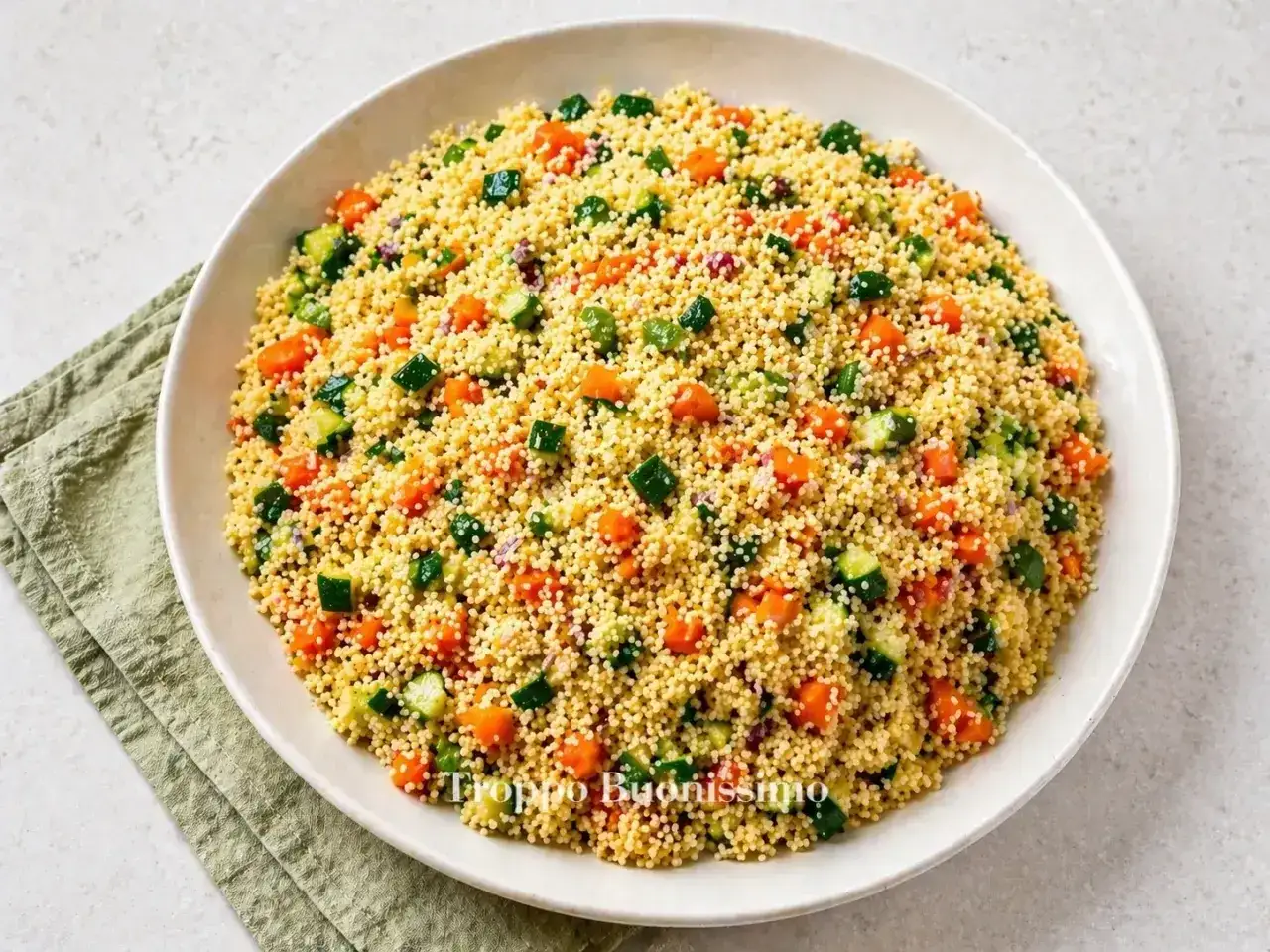 Un piatto invitante di cous cous con verdure colorate: carote, zucchine e cipolla rossa. Perfetto per un pasto leggero e gustoso.