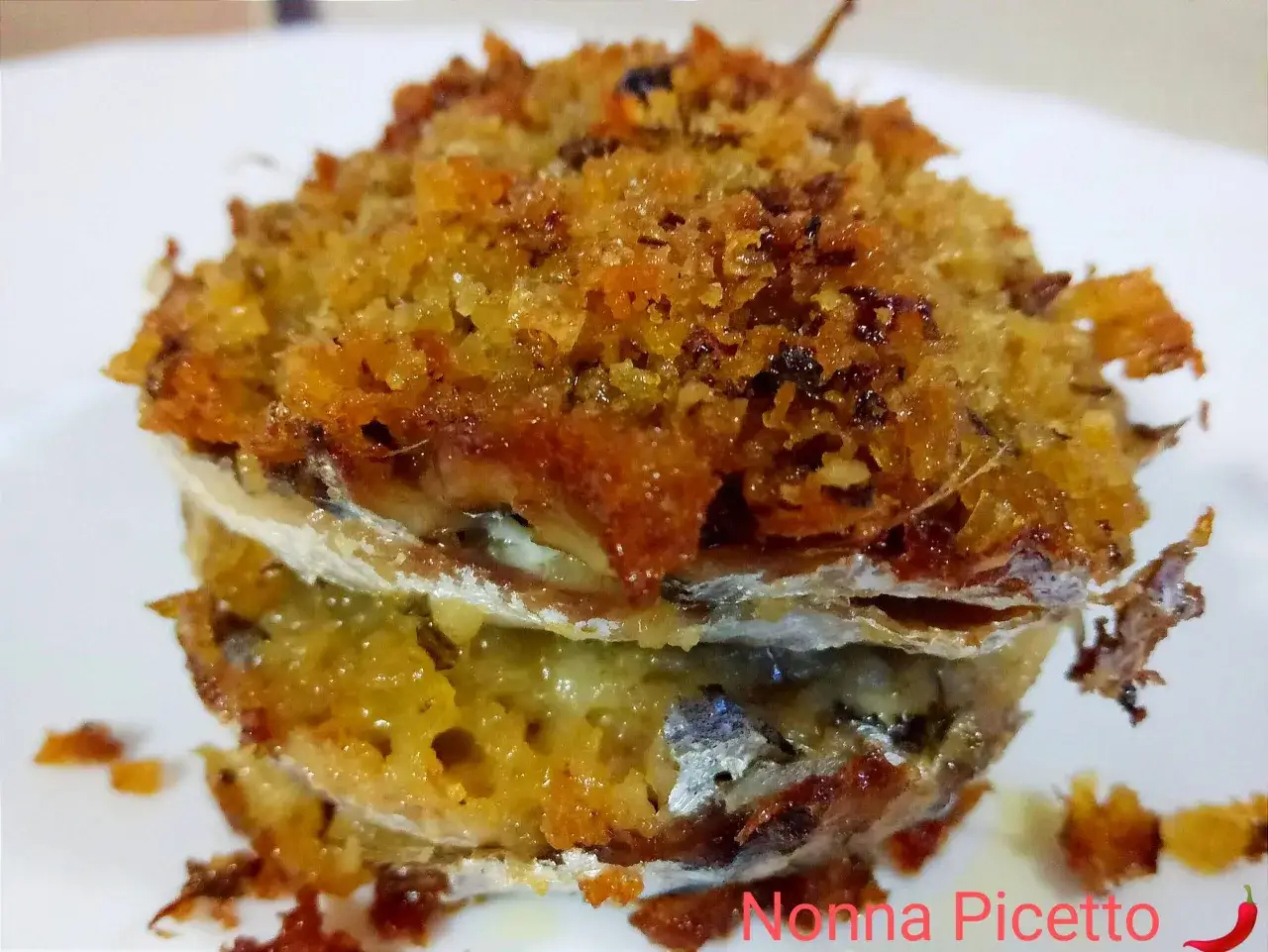Tortino di alici impanato e dorato, con strati di pesce e ripieno gustoso. Un classico della cucina di mare.