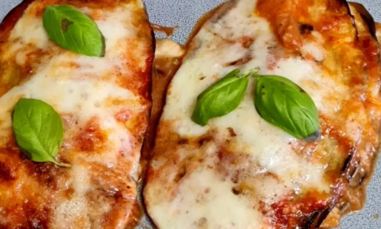 Parmigiana di melanzane in friggitrice ad aria, dorata e filante, guarnita con basilico fresco. Un piatto gustoso e leggero.