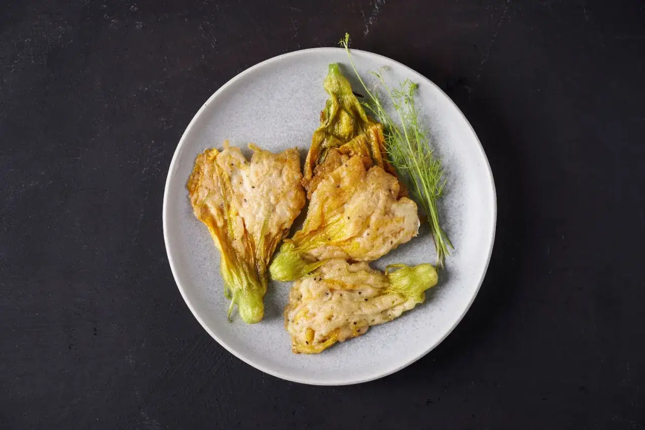 Deliziosi fiori di zucca in padella, dorati e croccanti, con un leggero velo di pangrattato.