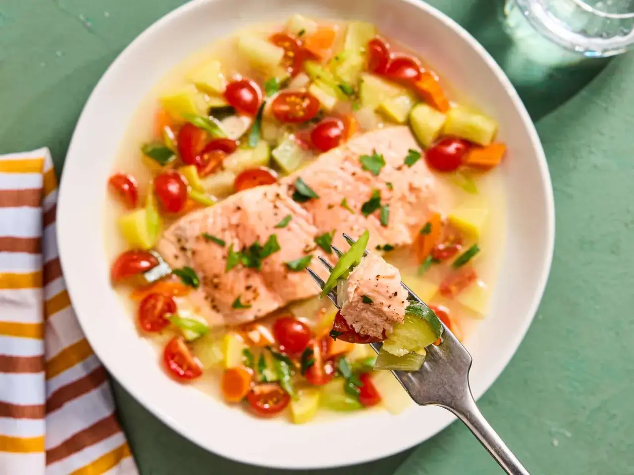 Salmone in brodo con patate, carote, pomodorini e zucchine. Un piatto leggero e saporito, perfetto per i contorni estivi.
