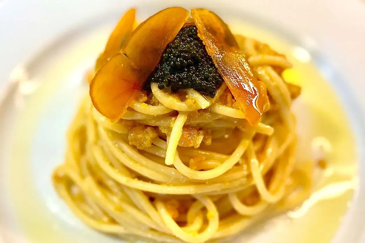 Spaghetti con la bottarga, guarniti con uova di pesce e scaglie dorate. Un piatto raffinato che celebra i sapori del mare.