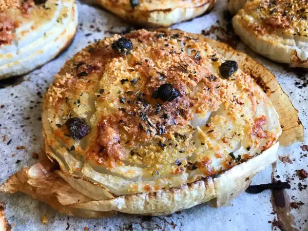 Cipolla Giarratana al forno, dorata e croccante, con olive nere e erbe aromatiche.