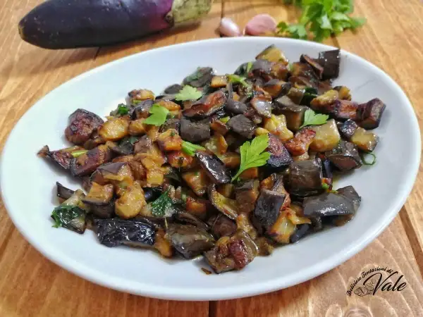 Un piatto invitante di melanzane al funghetto, tagliate a cubetti e saltate con erbe aromatiche, guarnito con prezzemolo fresco.