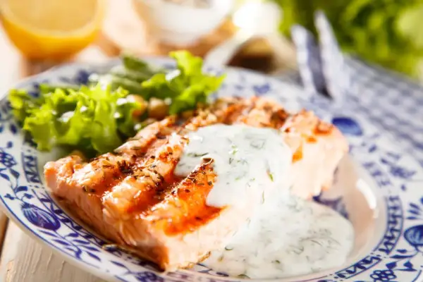 Salmone grigliato con salsa vierge e insalata fresca, un piatto leggero e gustoso.