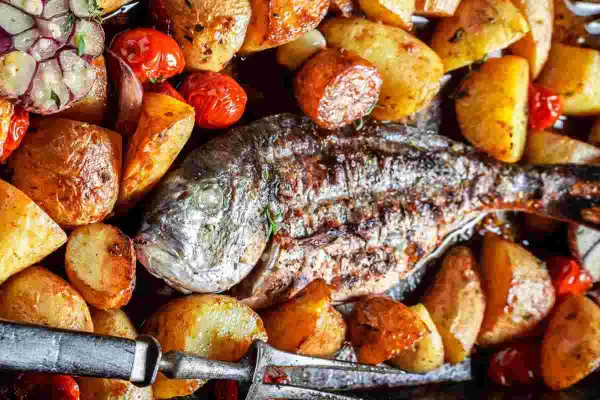 Orata alla ligure al forno, con patate arrosto, pomodorini e aglio. Un piatto succulento e profumato.