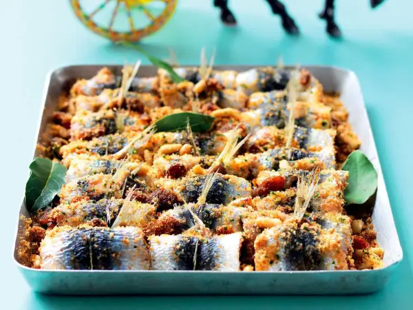 Sardine ricette: gustose sardine al forno con pangrattato, pinoli e pomodorini, pronte per essere gustate.