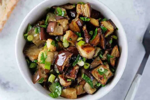 Melanzane viola ricette in padella: cubetti dorati e saporiti, conditi con erbe fresche, pronti per essere gustati.
