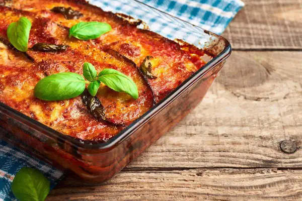 Parmigiana di melanzane in friggitrice ad aria, dorata e profumata, guarnita con basilico fresco. Un piatto gustoso e leggero.