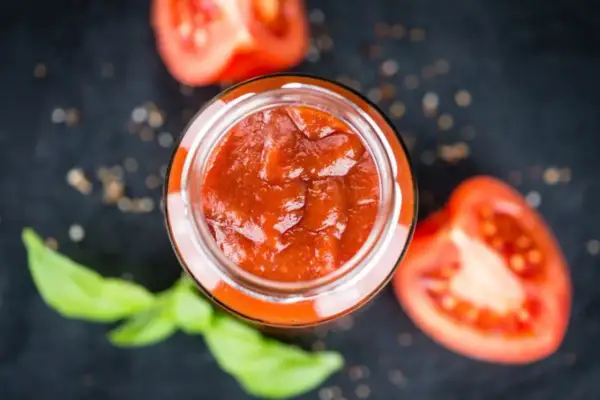 Un vasetto di sugo al pomodoro fatto in casa, con pomodori freschi e basilico, pronto per condire la pasta.
