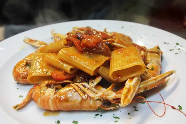 Rigatoni con scampi e pomodorini, un classico dei primi piatti della domenica, fumante e invitante.