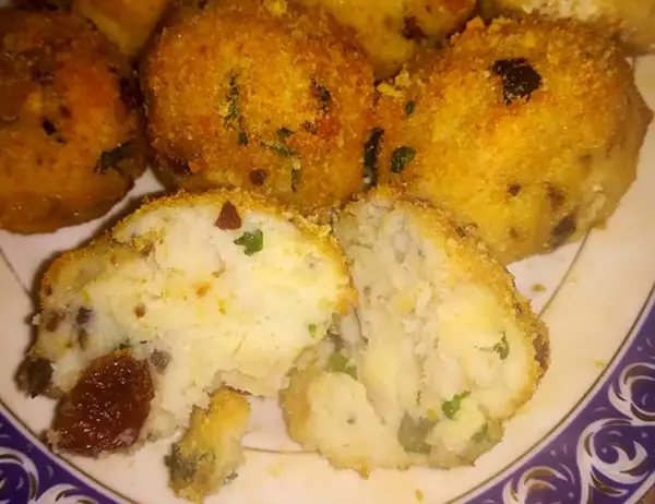Polpette di merluzzo dorate e croccanti, una metà tagliata rivela un interno morbido con erbe aromatiche e pezzetti scuri.